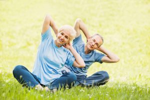 Cheerful mature couple doing exercises in park.